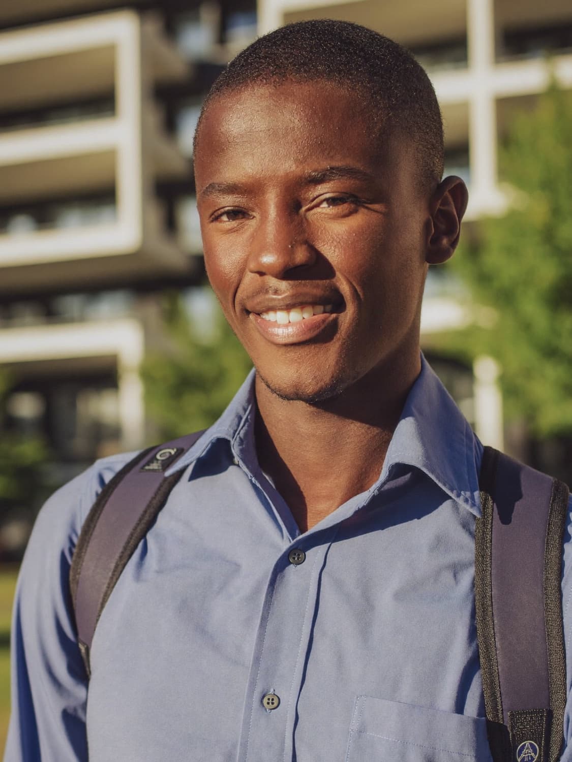 A smiling student on campus holding his notebook